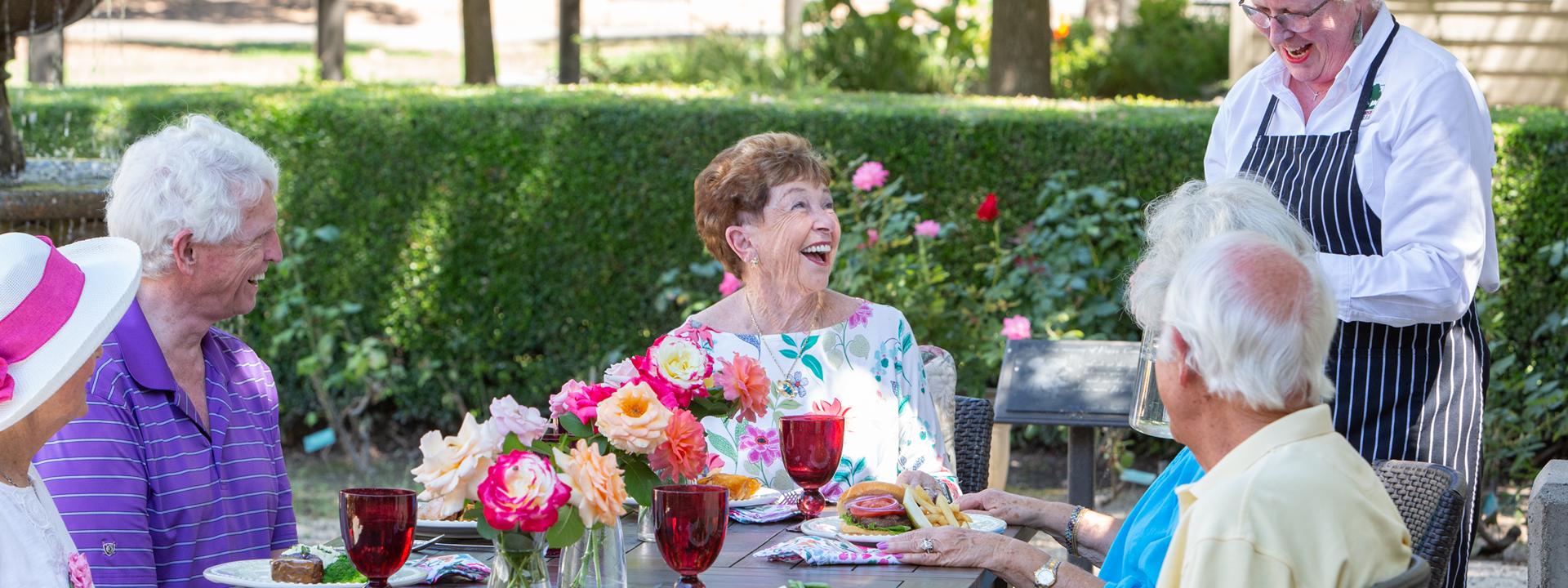 Residents laughing and enjoying lunch on the patio