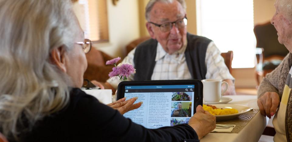 Three resident having breakfast and reading the news.