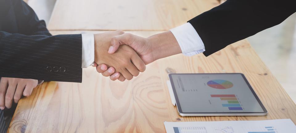 Hand shake with computer on the table