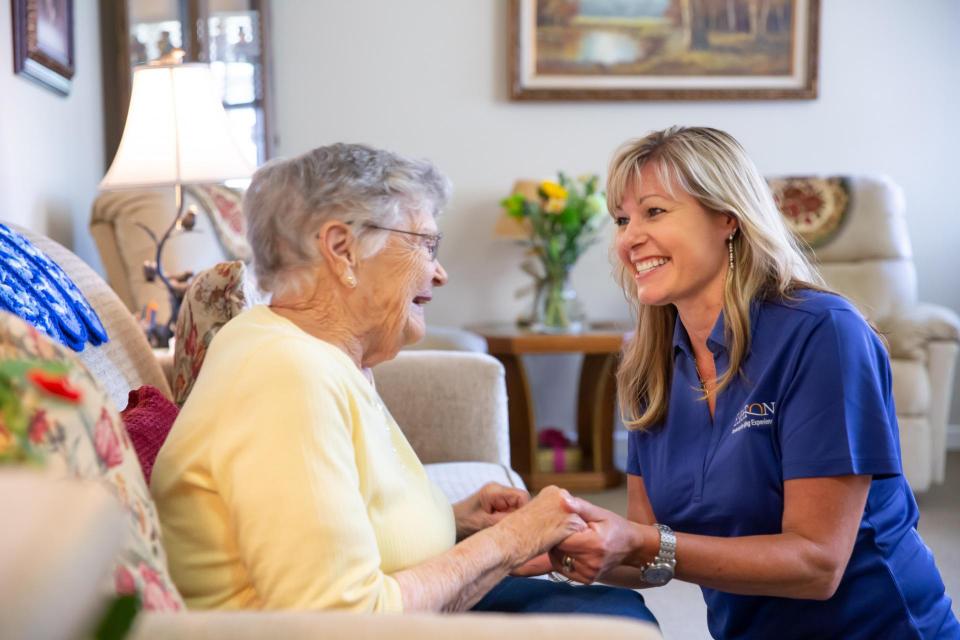 Resident and staff holding hands and laughing 