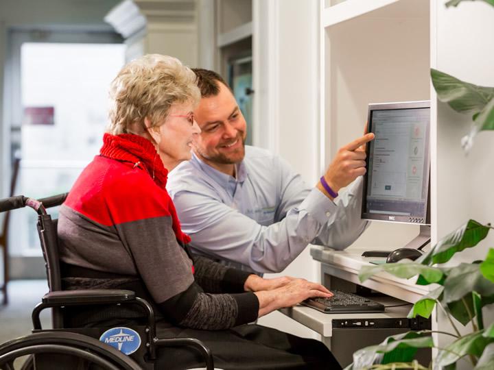 Staff showing resident how to use computer programs.