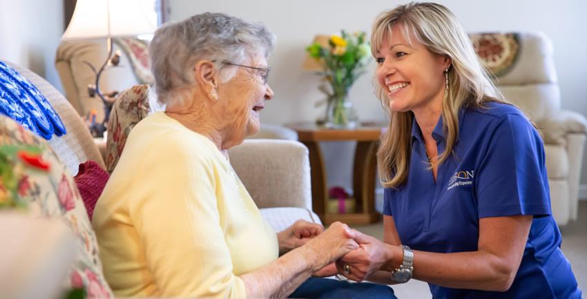 Resident and staff holding hands and smiling at each other