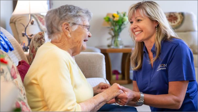 Resident and staff holding hands and smiling at each other