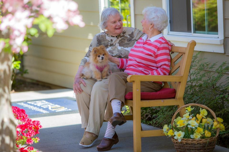 Two women sitting outside on a bench talking.