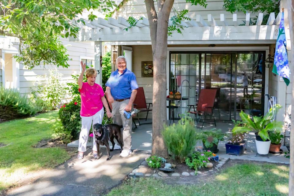 Couple outside their cottage waving to friends.