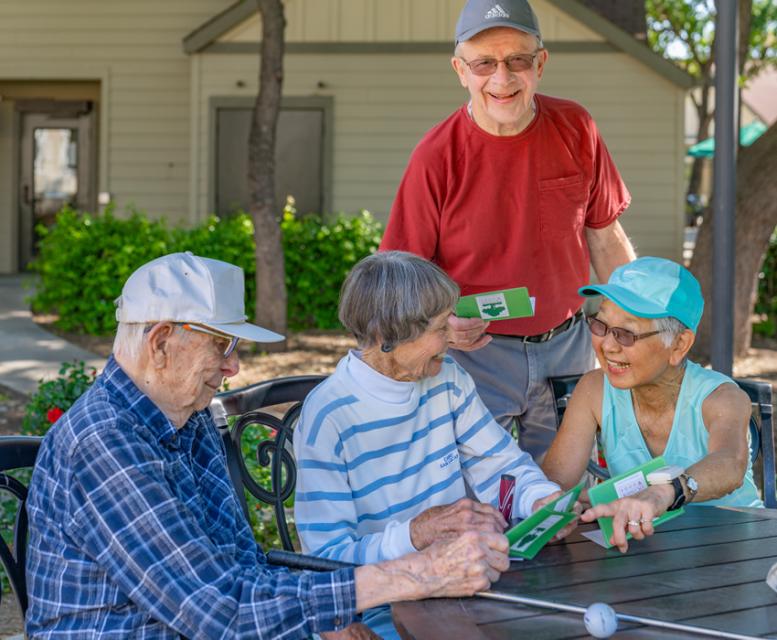 Two couples sitting at a patio table comparing their golf scores