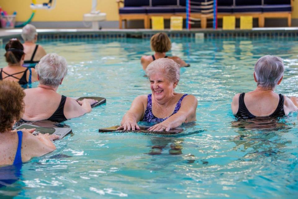 Several residents in the indoor pool enjoying a water aerobics class