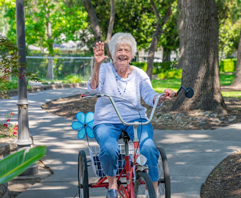 Resident riding her bike, smiling and waving