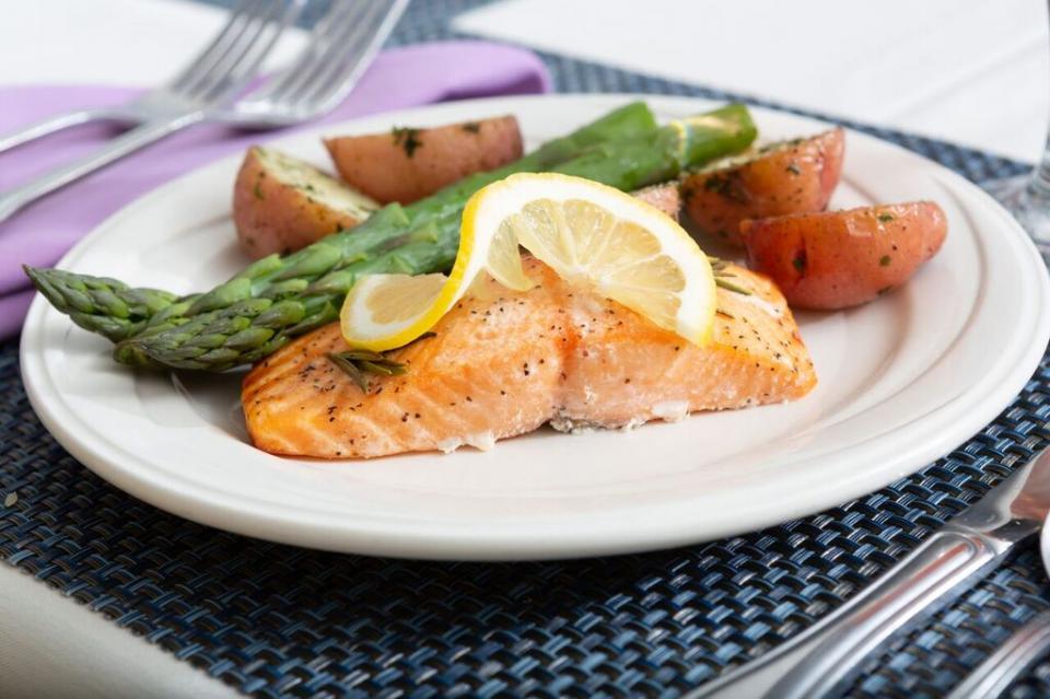 A dinner plate with salmon, asparagus, roasted red potatoes.