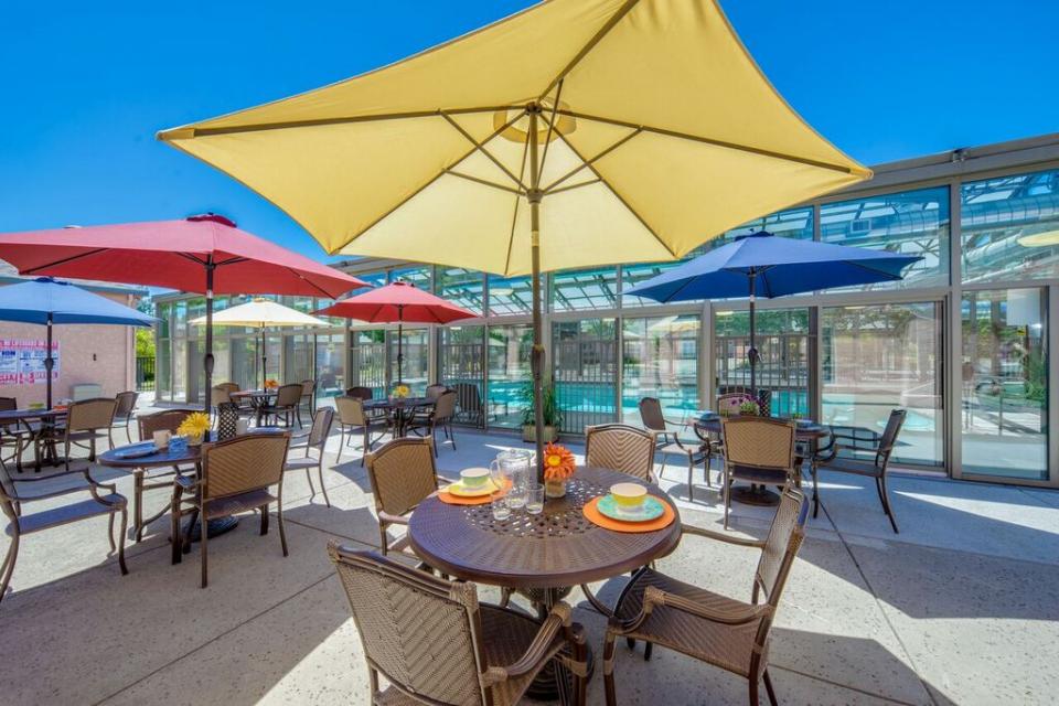 Patio tables with colorful table umbrellas next to the indoor swimming pool