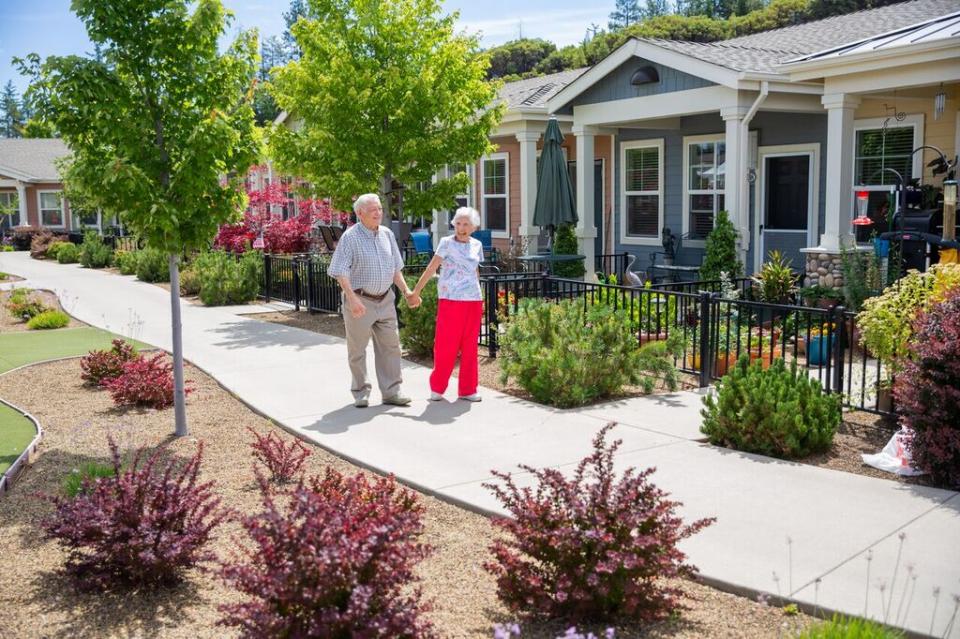A smiling couple holding hands,  walking along the patio homes walking path