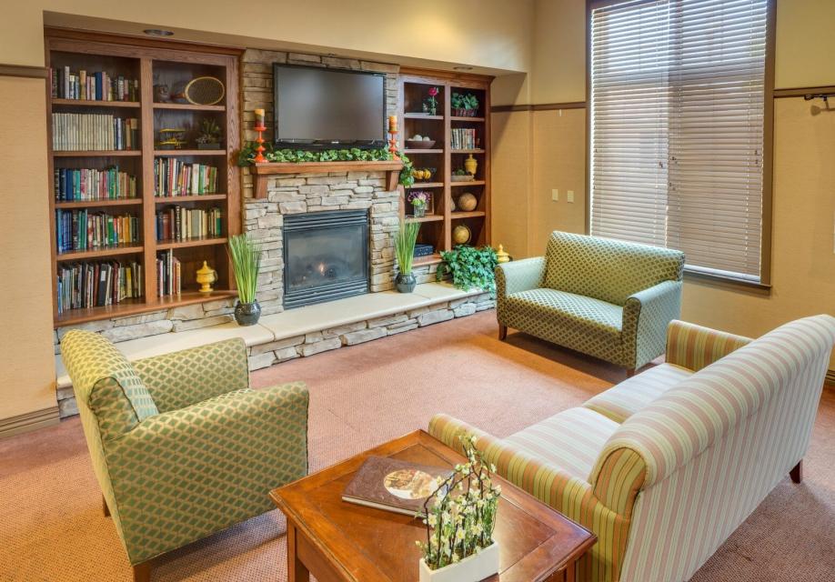 Lobby area with couch, love-seat, chair, fireplace and a entertainment center with books and TV