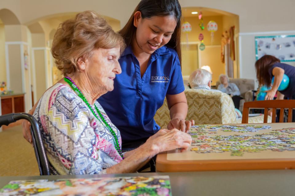 Two women putting a puzzle together in the activity room.