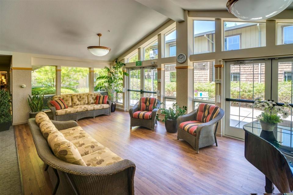 Common social area with couches, chair, piano and plants.