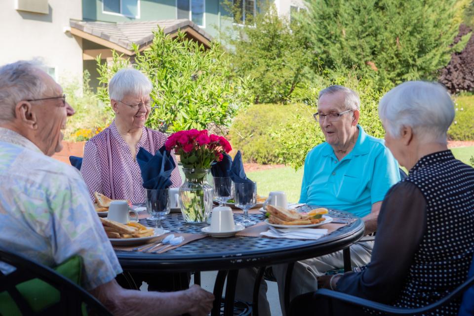Four residents sitting around the outside patio table socializing