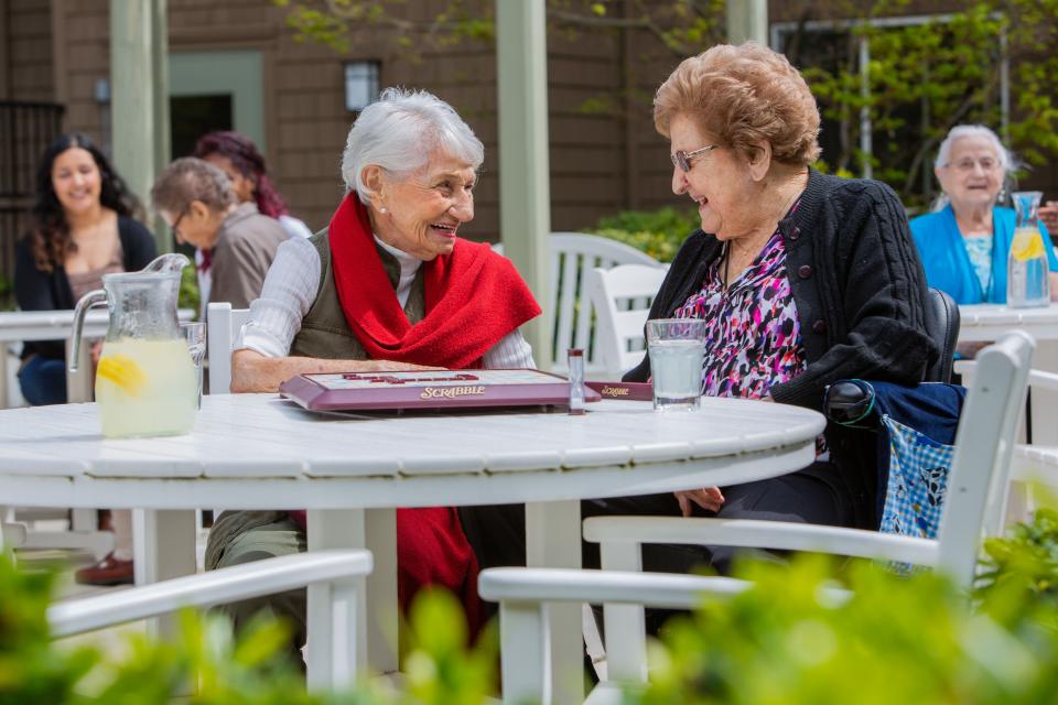 Residents sitting outside on the patio smiling and talking to each other.