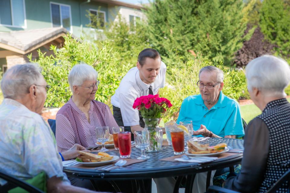 Dining staff serving  two couples lunch on the patio