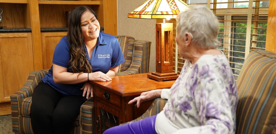 Resident and staff sitting in the lobby smiling and talking