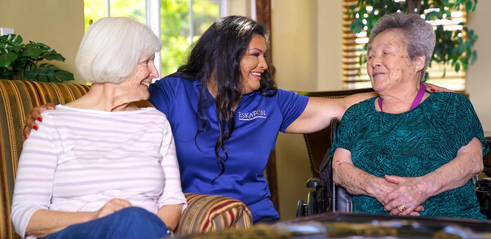 Staff and two resident women smiling and visiting with each other