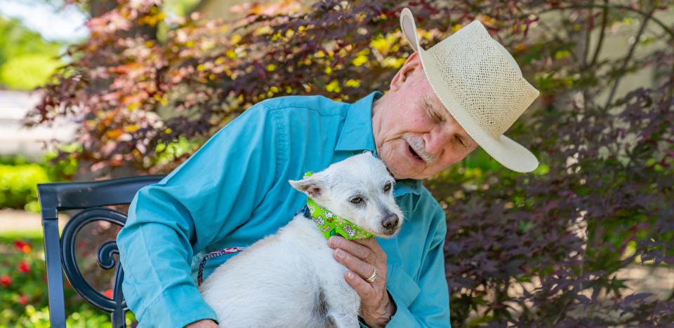 Man sitting on a bench with his dog.