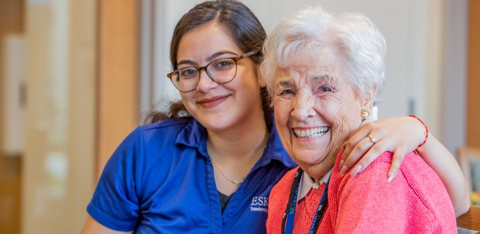 Staff with her arm around a resident and both smiling